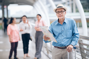 Asian senior man traveler in downtown hold on map and looking camera