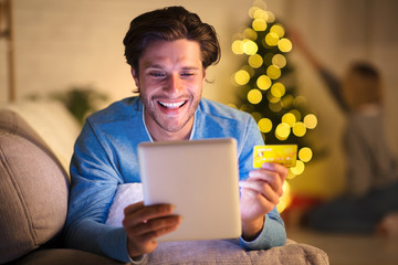 Handsome man shopping online on tablet on New Year's eve