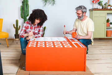 Couple painting furniture with brush at home
