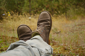 Legs of traveller. Brown shoes on grass background. Feet in old boots 