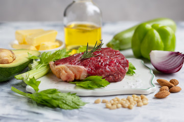 Meat, vegetables and oil on marble background.  Keto diet concept. Low carb and healthy fats. Closeup