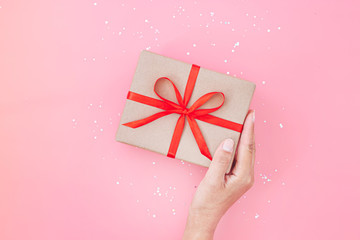Female hands holding present box or gift box package in the craft paper