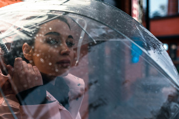Pretty girl holding umbrella and strolling on rainy autumn day. photo looks like film frame or...