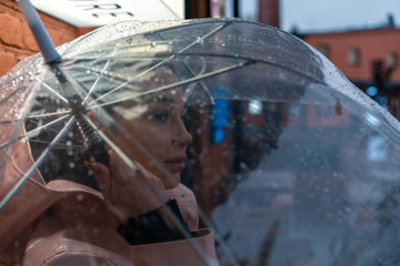 Pretty girl holding umbrella and strolling on rainy autumn day. photo looks like film frame or...
