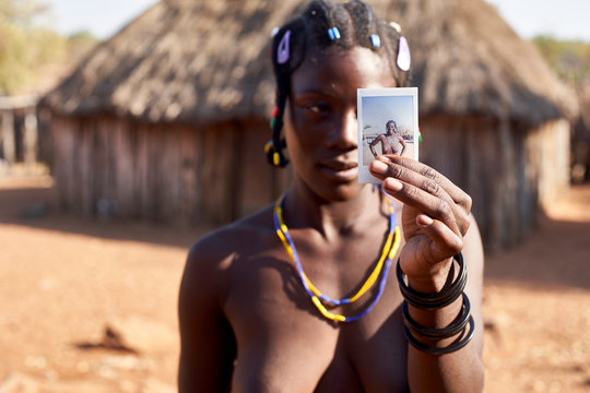 Mudimba tribe woman showing a picture of herself, Canhimei, Angola.