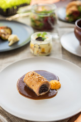 Different tasty dishes on the restaurant table, meat roll on the plate