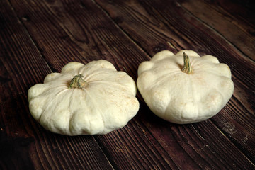 Two white pattypan squashed on dark wooden board, whole raw vegetable