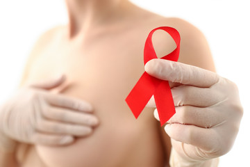 Female hand in gloves holding red ribbon cancer symbol breast closeup on doctor mammology clinic...