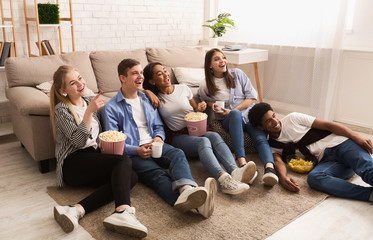 Happy friends watching comedy film and eating popcorn