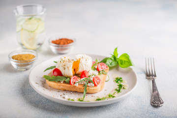Healthy breakfast. Poached egg on toasted toast with a glass of detox lemon cucumber water. copy space