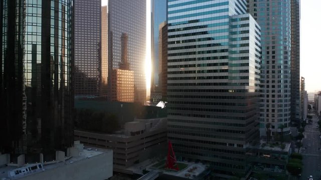 Slowly rising up together with the sun next to tall skyscrapers in the financial district downtown Los Angeles, cinematic shot, perfect for motivation, development and industrial videos.