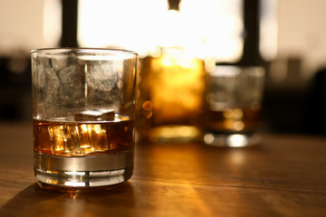 Fingerprint on glass with whiskey stands wooden oak table background. Alcohol addiction concept