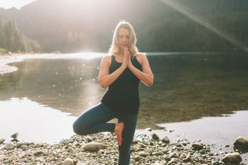 A woman stretching and practicing yoga on a beach at sunrise