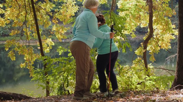 Happy active elderly women have fun in the park and run one after another in a circle during a Nordic walking exercise.