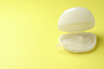 Plastic mouthguards for teeth whitening in a case on a yellow background