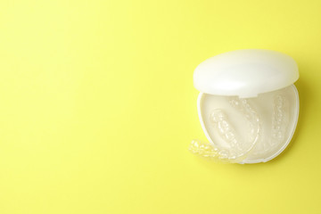 Plastic mouthguards for teeth whitening in a case on a yellow background, top view