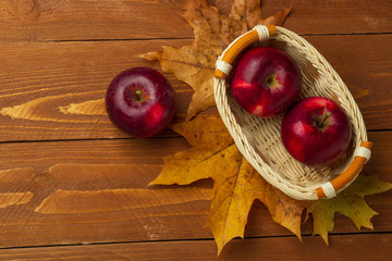 Small basket with red autumn leaves on a wooden table