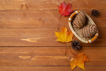 Still life with a view of a basket with pine cones and autumn leaves