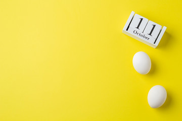 World Chicken Egg Day, October 11, calendar and white eggs, on a yellow background