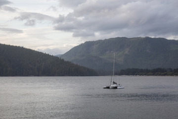 Sailboat parked in the ocean near Port Renfrew during a cloudy summer day. Located in Vancouver Island, British Columbia, Canada.