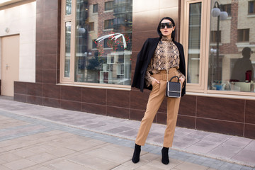 Fashion woman in sunglasses and suit. Standing in the city