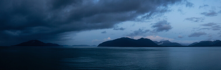 Beautiful Panoramic View of American Mountain Landscape on the Ocean Coast during a cloudy and rainy sunrise in fall season. Taken in Glacier Bay National Park and Preserve, Alaska, USA.
