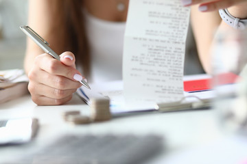 Woman hold silver pen and check in hand. Home budget concept. Wife checks a notes and brings balance