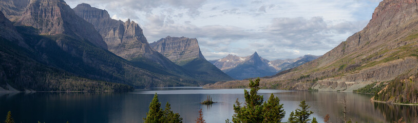 Beautiful Panoramic View of a Glacier Lake with American Rocky Mountain Landscape in the background during a Cloudy Summer Morning. Taken in Glacier National Park, Montana, United States.