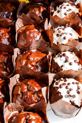 Chocolate muffins with chocolate chips in brown paper on a wooden background. Street food concept