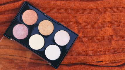 box of highlighter and glitter on woolen scarf 