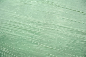 Raindrops on green plastic surface close-up.