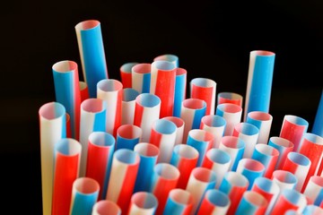 Pack of colorful drinking straws on a dark black background in landscape orientation