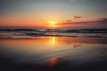 Obraz premium Beautiful sunset ocean view with waves and reflection. Praia da Bordeira at the Algarve Coast in Portugal, Atlantic Ocean
