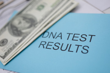 Cash dollars with blue envelope with inscription dna test result lie on table in office medical examiner