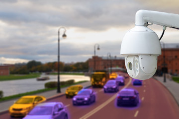 The concept of video surveillance and security technology. CCTV camera on the background of a road bridge with traffic in cloudy weather