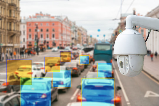 The concept of video surveillance and security technologies. Surveillance camera on the background of the city road with cars