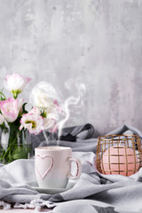 Having a cup of coffee with chocolate, flowers eustoma and candle on blanket in bed. Holiday concept
