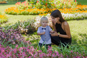 Young mother with her little son in a flower bed.