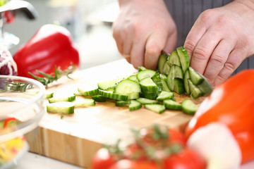 Male Hands Chopping Fresh Cucumber Small Pieces. Man Cutting Green Ingredient to Slices by Sharp Knife on Wooden Board. Healthy Culinary Recipe. Chopped Dieting Dish with Cuke Horizontal Photo