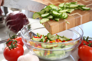 Green Chopped Cucumber Slices Pouring Glass Bowl. Healthy Dieting Salad Ingredient. Fresh Organic Vegetable. Hot Chili Pepper and Small Cuke Pieces. Vegetarian Kitchen. Horizontal View Photography