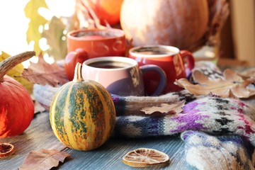 Three cups of coffee, pumpkins, leaves, a woolen scarf on a window background, the concept of home comfort, family, Thanksgiving, autumn season