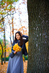 woman posing with autumn leaves in city park, outdoor portrait
