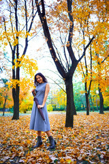 woman posing with umbrella and autumn leaves in city park, outdoor portrait