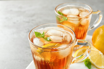 Cups of refreshing iced tea on light table