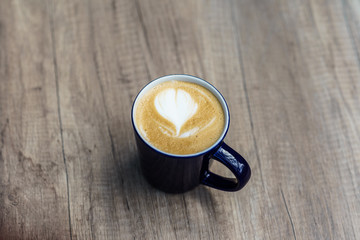 A cup of cappuccino with latte art on wooden table
