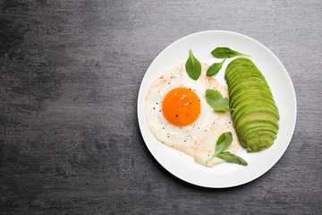 Tasty breakfast with fried egg and avocado on grey table, top view. Space for text