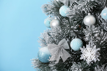 Fototapeta na wymiar Beautiful Christmas tree with decor against light blue background, closeup. Space for text