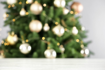 Empty white wooden table and blurred fir tree with Christmas lights on background, bokeh effect....