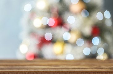 Empty wooden table and blurred fir tree with Christmas lights on background, bokeh effect. Space for design