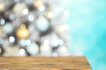 Empty wooden table and blurred fir tree with Christmas lights on background, bokeh effect. Space for design